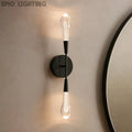 Modern wall sconce with two light bulbs on a neutral wall.